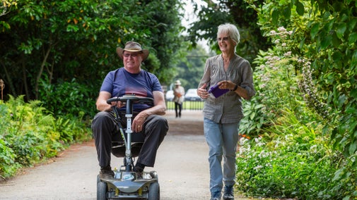 Two visitors, one of whom is in a wheelchair, walking along the path at Tredegar House in Newport